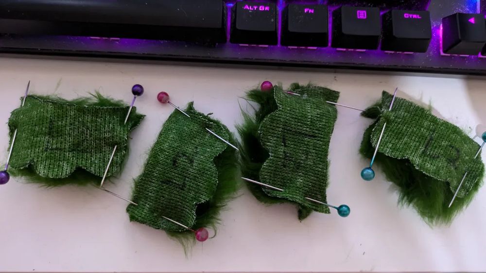 A photo of four pinned pieces of fluffy green fabric on a desk