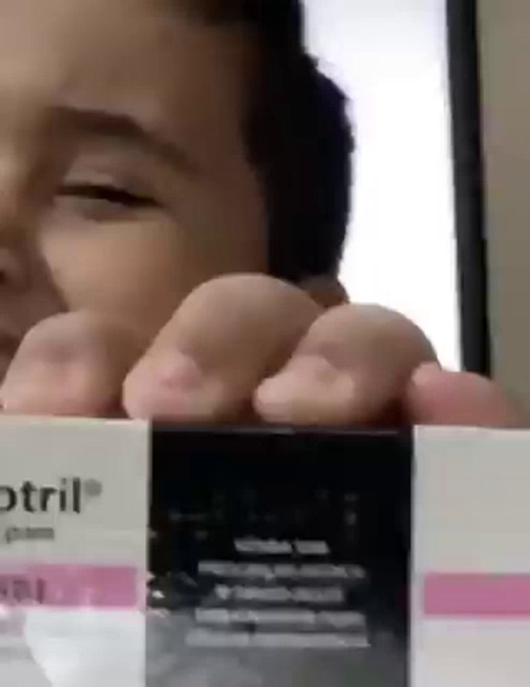 a person is holding a box that says optril on it .