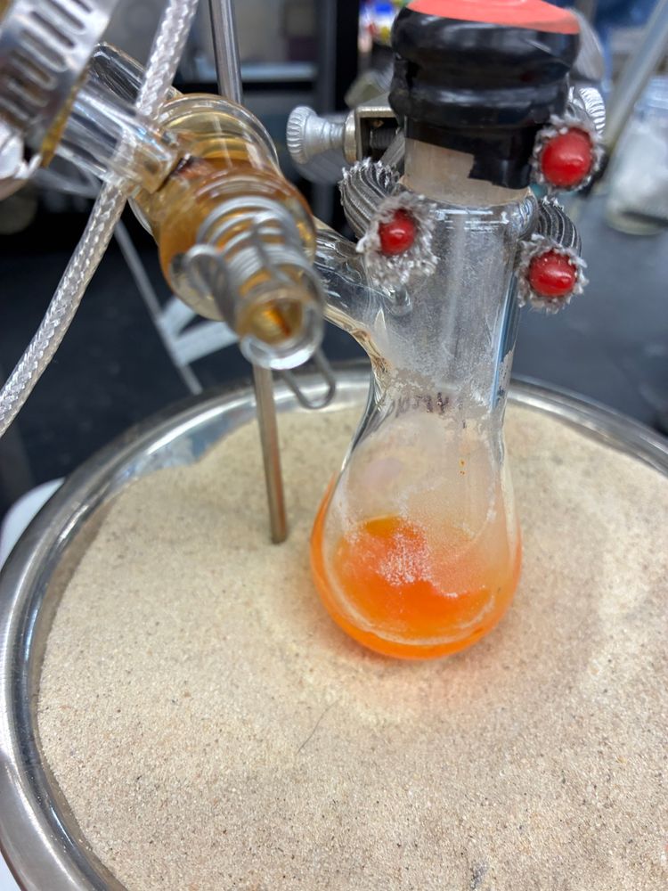 50 mal Schlenk flask with 5 mL of bright orange solution, in a sand heating bath 