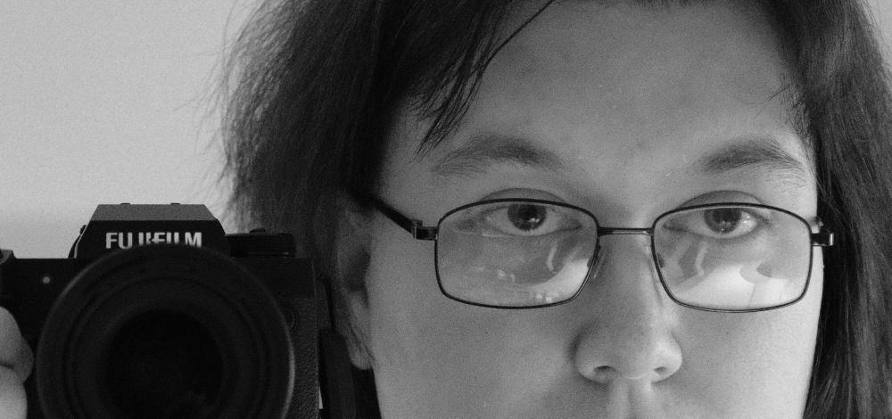 A cropped picture of me infront of a mirror leaning over with the camera on the left of the image and me on the right 