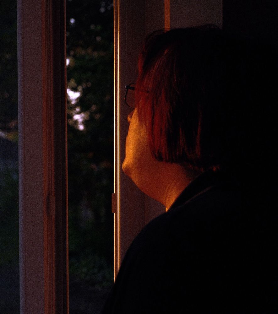 Portrait of an unknown person leaning against a sunlit windowsill 