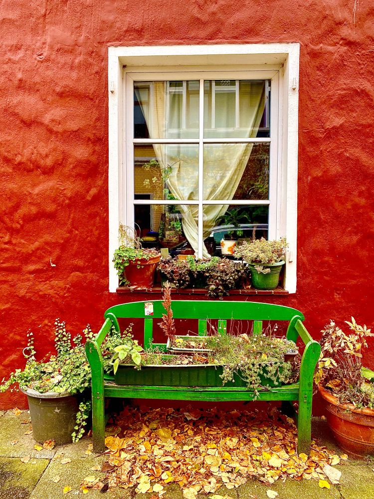 Fenster mit Bank davor, rote Hauswand