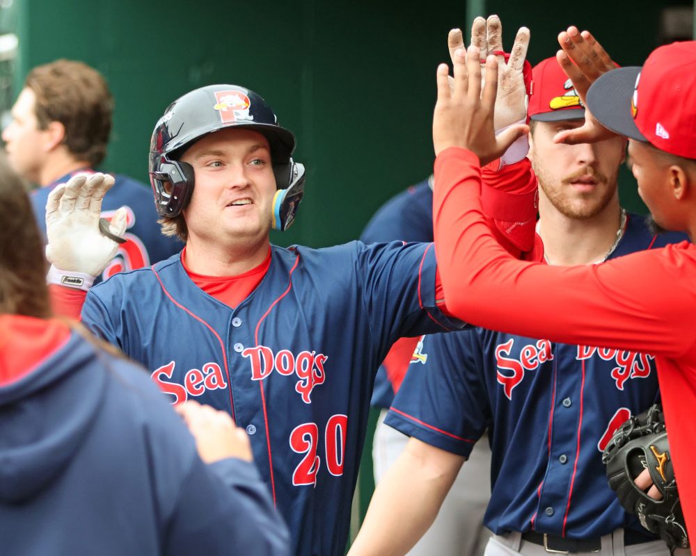 Portland Sea Dogs batter Blaze Jordan receives high-fives from teammates in the dugout after his home run against the New Hampshire Fisher Cats.