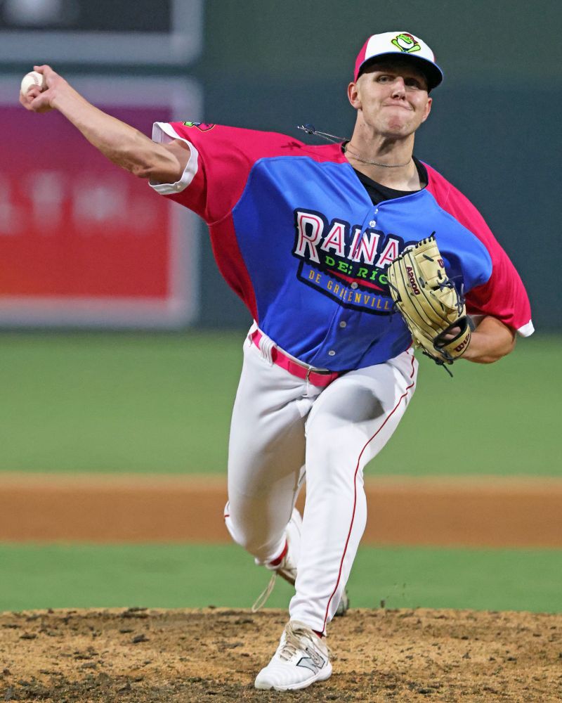 RHP Isaac Stebens pitches at Fluor Field in the Ranas de Rio uniform (white pants, blue jersey with very pink sleeves, blue/white/pink cap) of the Greenville Drive.