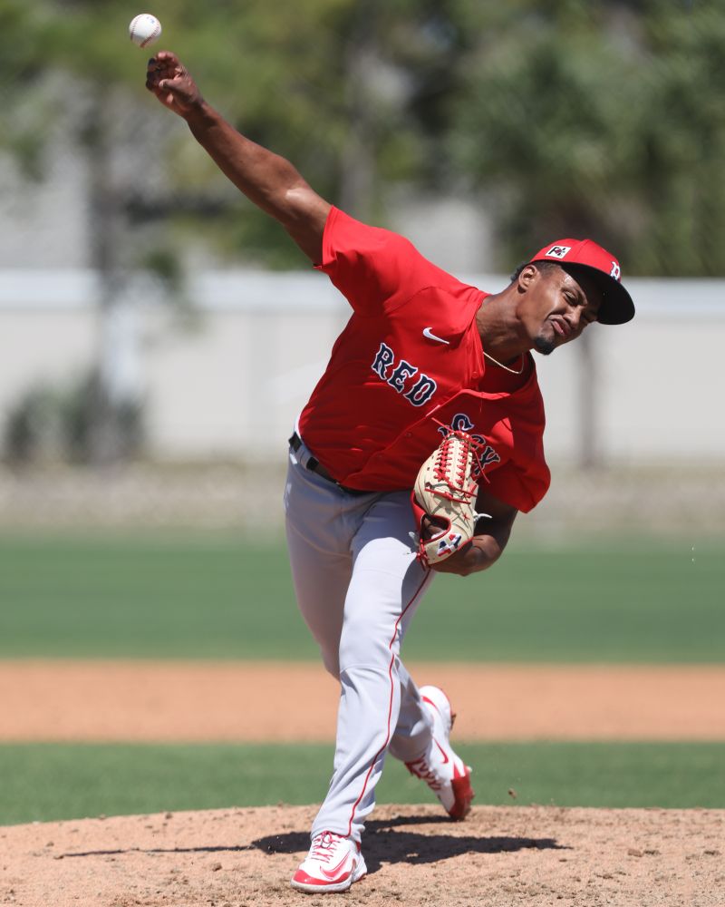 Red Sox minor league righthander Yordanny Monegro is shown pitching as he releases the ball at full extension. He wears a red Red Sox jersey and gray pants and holds a tan glove with red stitching.