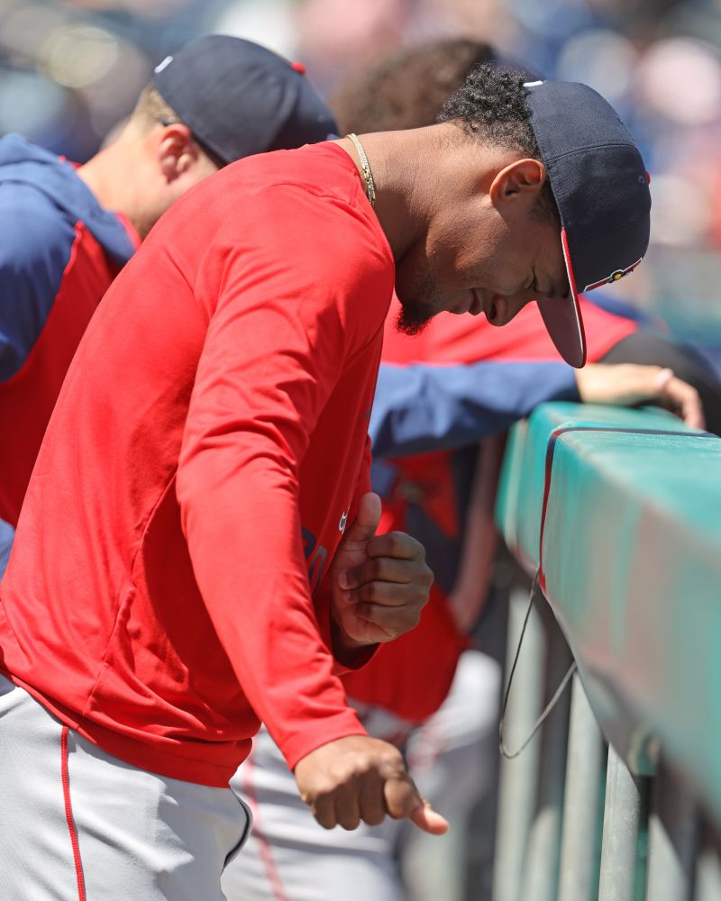 Red Sox minor league righthander Yordanny Monegro is shown dancing in the Portland Sea Dogs dugout, smiling as he looks down and swings his hands to his right. He wears a red sweatshirt and gray pants.