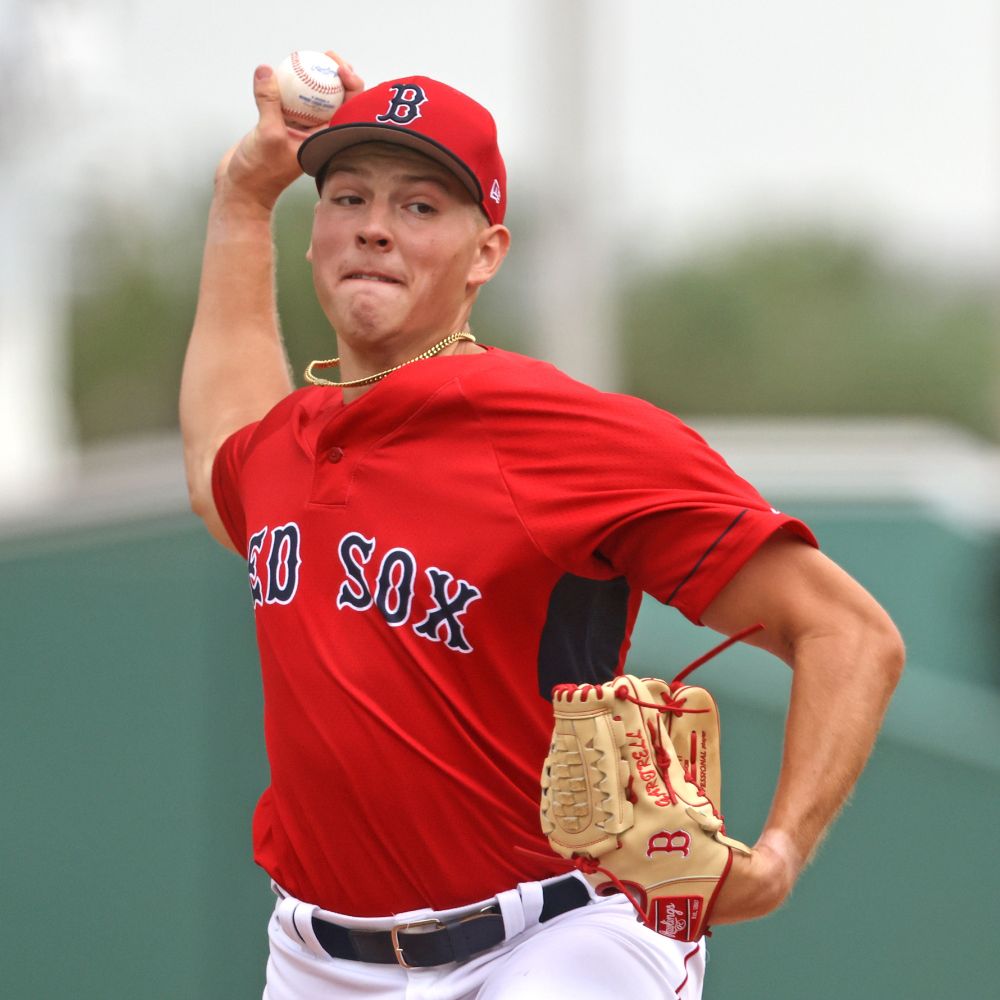 Right-handed pitcher Joey Gartrell is shown in his pitching motion with the ball coked behind his head at JetBlue Park in Fort Myers. He wears a red Red Sox jersey and white pants and has a tan glove on his left hand.