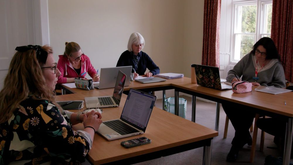Four women of various ages studying together at a set of desks
