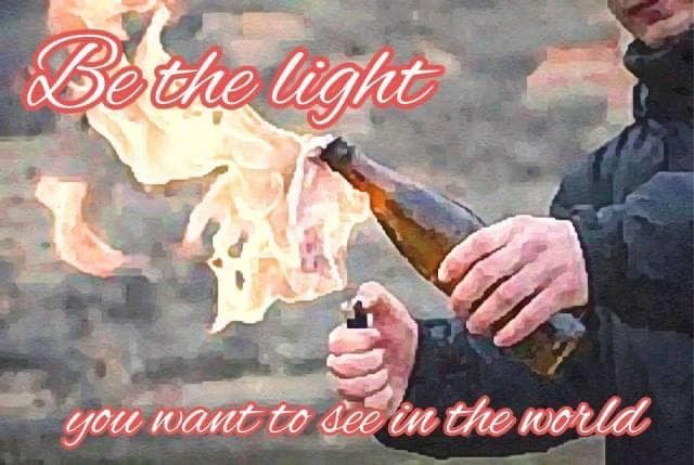 An image of someone in what looks like a black windbreaker, lighting a brown-bottle molotov cocktail in his left hand with a lighter in his right. Superimposed on the image in bright flowery script is "Be the light you wish to see in the world." 
