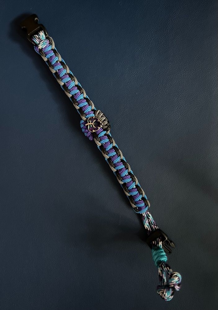 woven bracelet in blue and purple, outlined with grey and black, with small metal leaf (with same colors) in the center