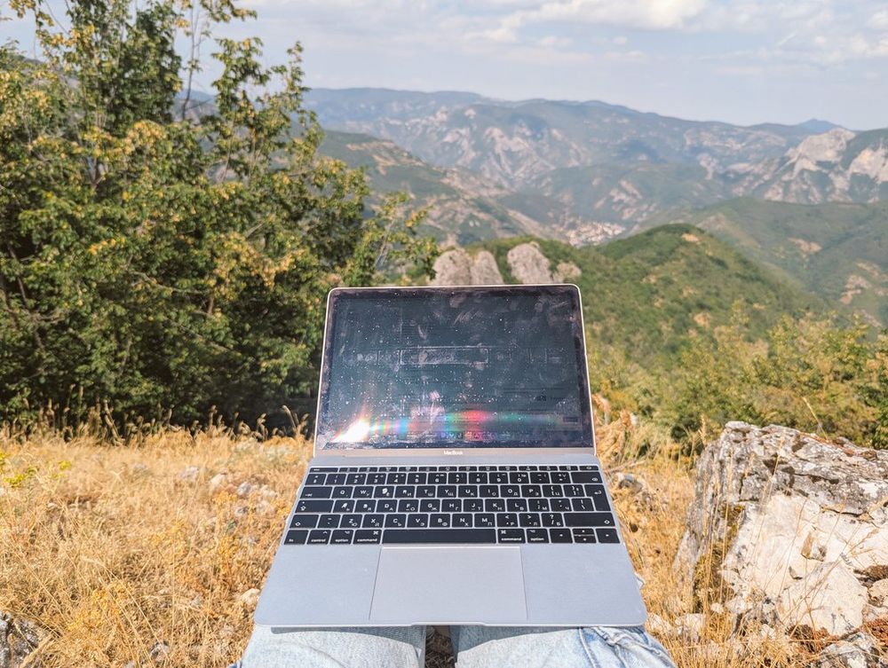 Pic of my lap with a 12 inch MacBook, background is literally a view from a mountain's summit 