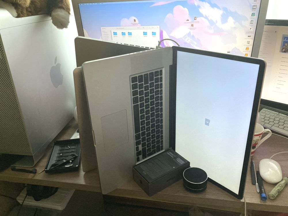 Picture of two 17" MacBook Pros, standing on their sides open, with one  in a V shape and the other right against it open a lot wider with the screen visible showing a question mark folder
