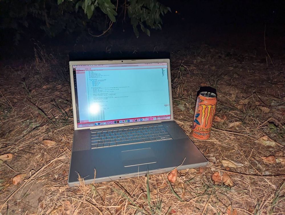 Picture of an A1261 17" MacBook Pro sitting on the ground in a forest with a can of Monarch Monster next to it