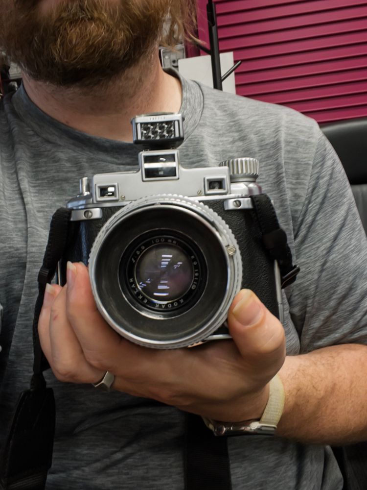 A person holding a Kodak Medalist rangefinder camera in his left hand as described.