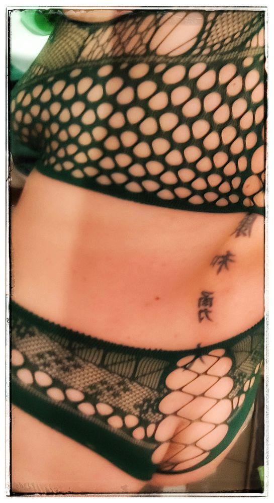 Oberkörper einer Person mit grünem, netzartigem, gemustertem Oberteil und passendem Unterteil, sichtbare Hautpartien durch das Muster. Rückseite 