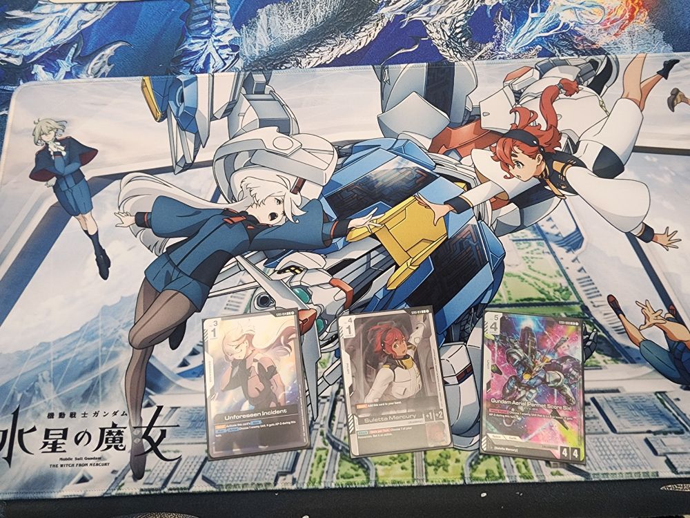 Three G-Witch cards from the new Gundam Card Game on a G-Witch playmat.