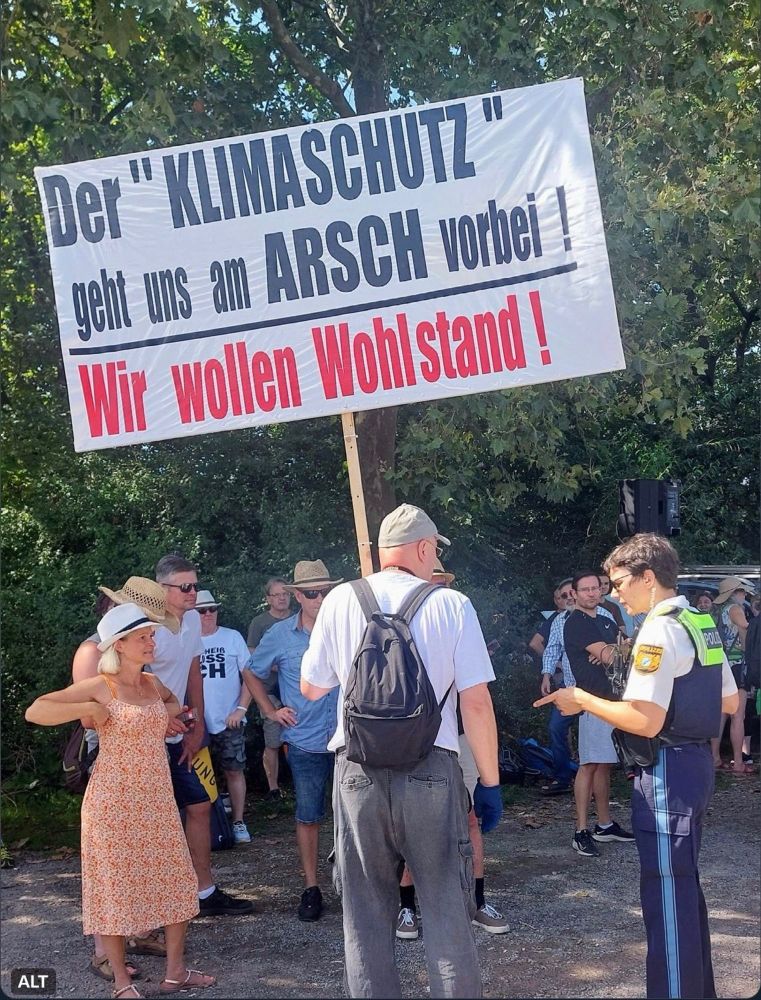 Demo, vermutlich Querdenker, ein älterer Herr hält ein großes Schild in der Hand mit Aufschrift „Der "KLIMASCHUTZ" geht uns am ARSCH vorbei !
Wir wollen Wohlstand!