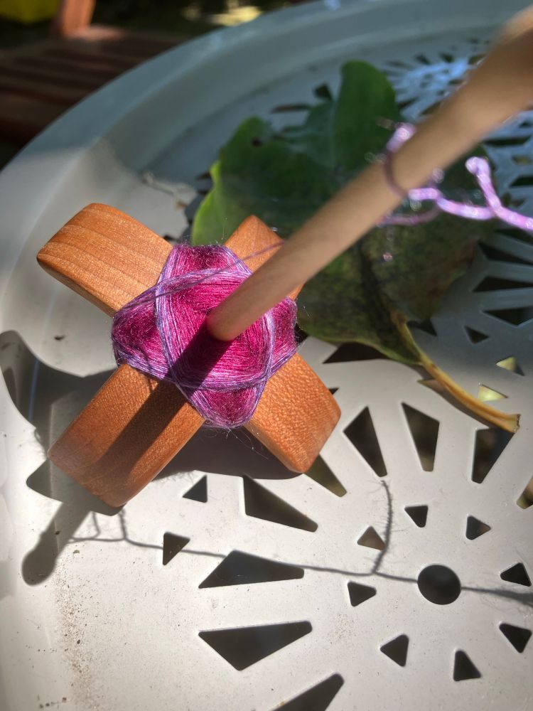 Second attempt to stop. The spindle rests on a gray side table. The cop is significantly bigger with a several-millimeter wide swath of lilac/purple wrapping on the outside layers. 