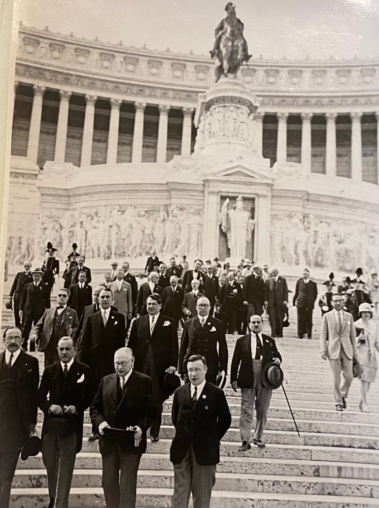 A large group of well-dressed men standing on the steps of a grand building.