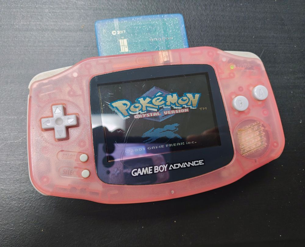 Pokemon Crystal Version title screen on an original model, transparent fuchsia Gameboy Advance for some early two thousands' vibes