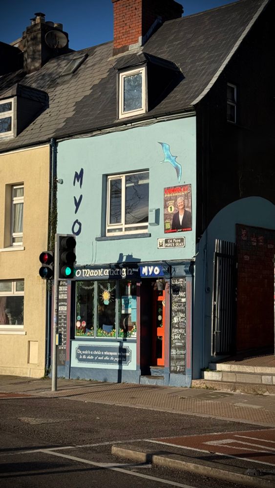 Image of the front of Cafe Myo, artwork featuring a gull and a poster from recent presidential elections featuring Catherine Connolly.