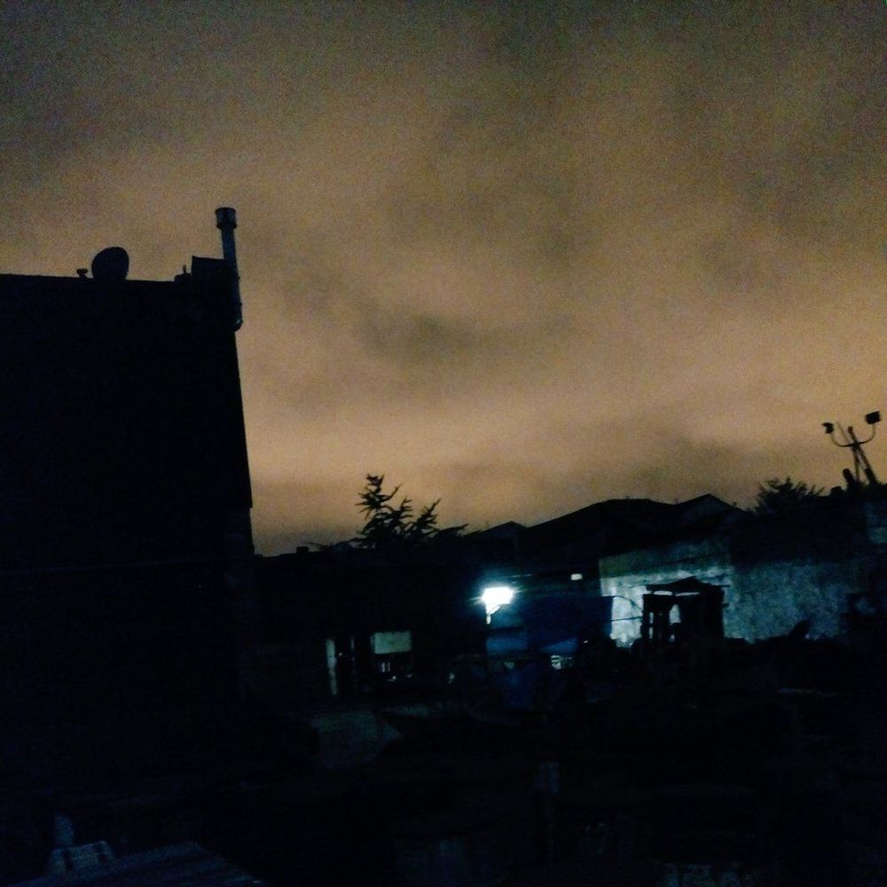 Moody photo of an orange night sky with silhouettes of a building