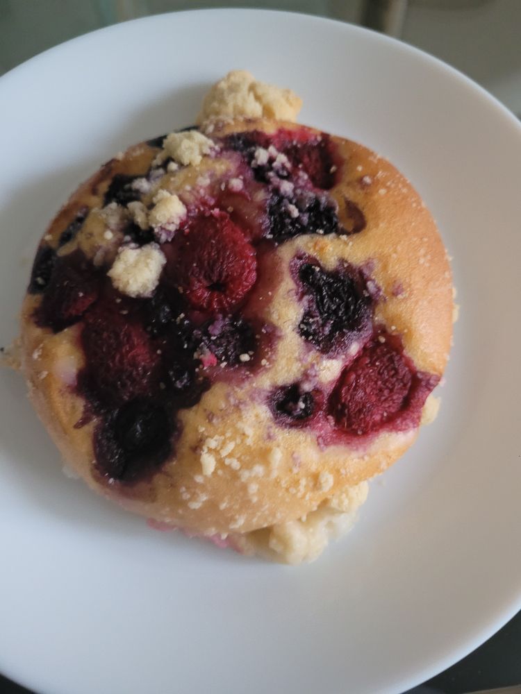 A little round cake topped with berries and crunchy crumble