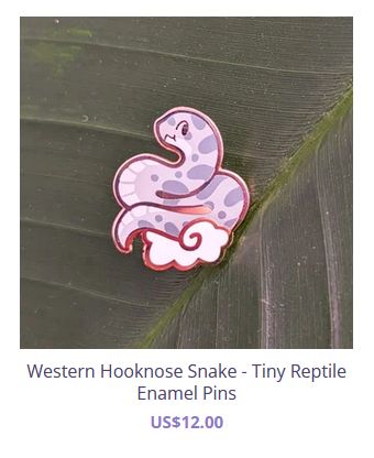 a screencap from the artist's shop of an enamel pin, a cute cartoony hognose snake rendered in pink and purple with a cheeky little smile