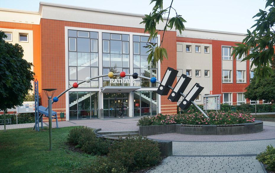 Rathaus von Schwedt, vor dem Gebäude steht eine Skulptur, die drei Aktenordner zeigt