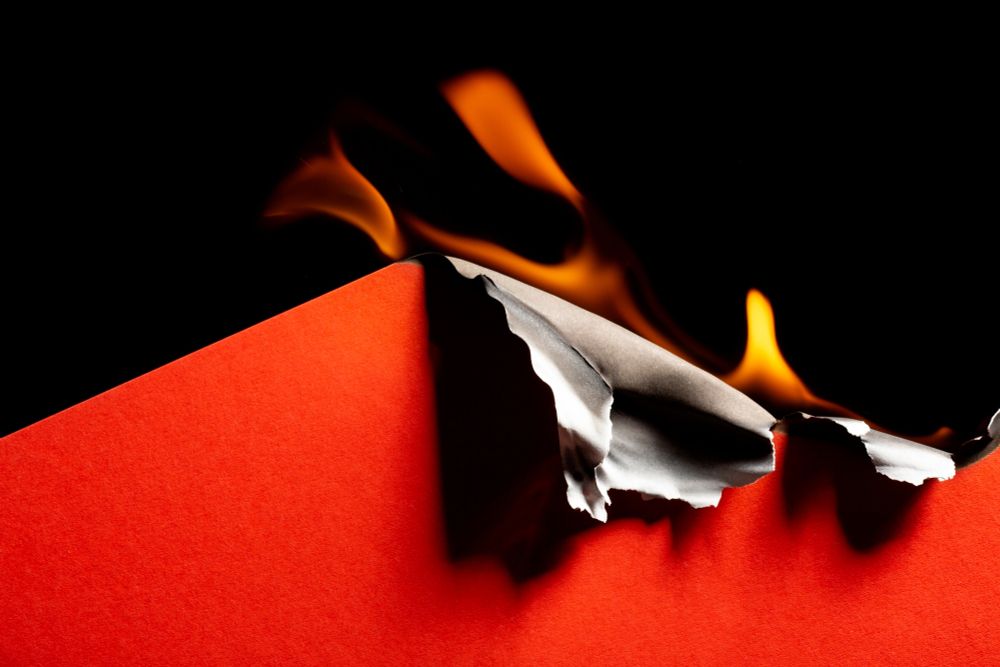 Ein rotes Blatt vor einem schwarzen Hintergrund fängt Feuer