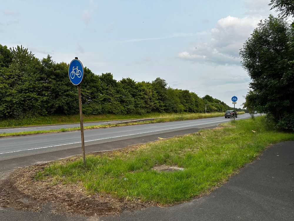 An der Emscherallee bei Dortmund-Mengede. Ein benutzungspflichtiger Radweg startet an der Kreuzung und mündet ca. 10 Meter weiter in eine vierspurige, autobahnähnliche Straße.