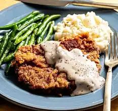Chicken fried steak with cream gravy, green beans, and mashed potatoes