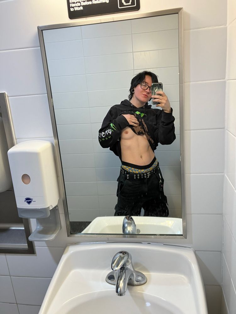 Sailor poses in a bathroom mirror, hoodie pulled up to reveal his chest and tummy to the people