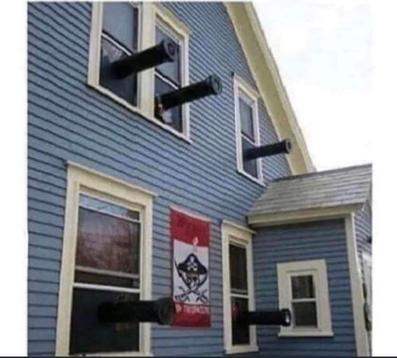 Side of a blue house with cannons coming out of every window and a pirate flag.