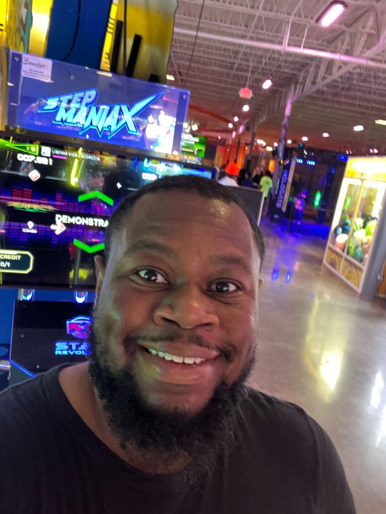 A selfie in front of a StepManiaX machine.