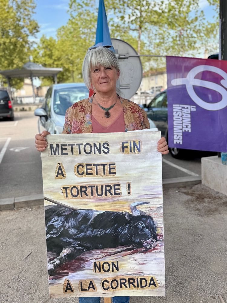 Rose  avec un drapeau insoumis et une pancarte avec un taureau «  Mettons fin à cette torture.  Non à la corrida » 