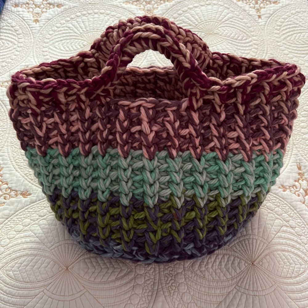 Thick crocheted round basket with handles. Morphs from green to aqua to maroon. Colours from each ball meshed and complimented so well. 