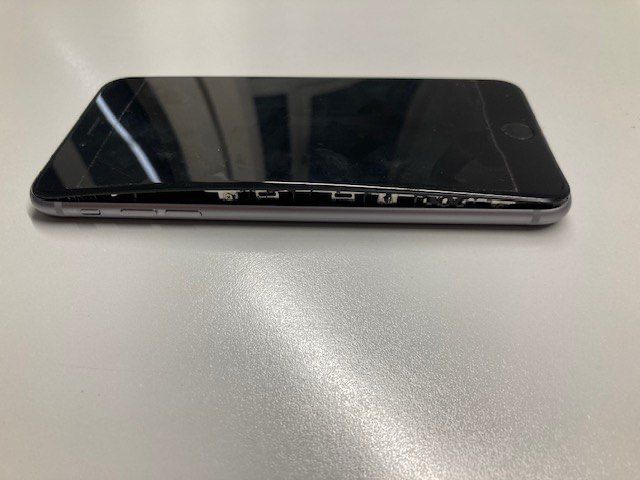 Ein iPhone liegt auf einem Schreibtisch. Der Akku ist so aufgebläht, dass es das Display aus dem Gehäuse biegt. 