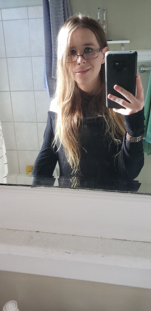 bunni (it/she) wearing a black sweater and a metal wristband