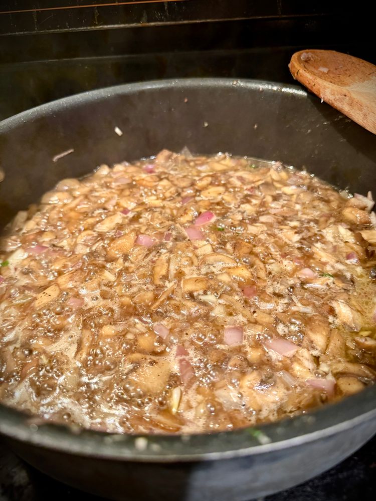 Shallot, mushroom, garlic wine reduction sizzling in a pan. 