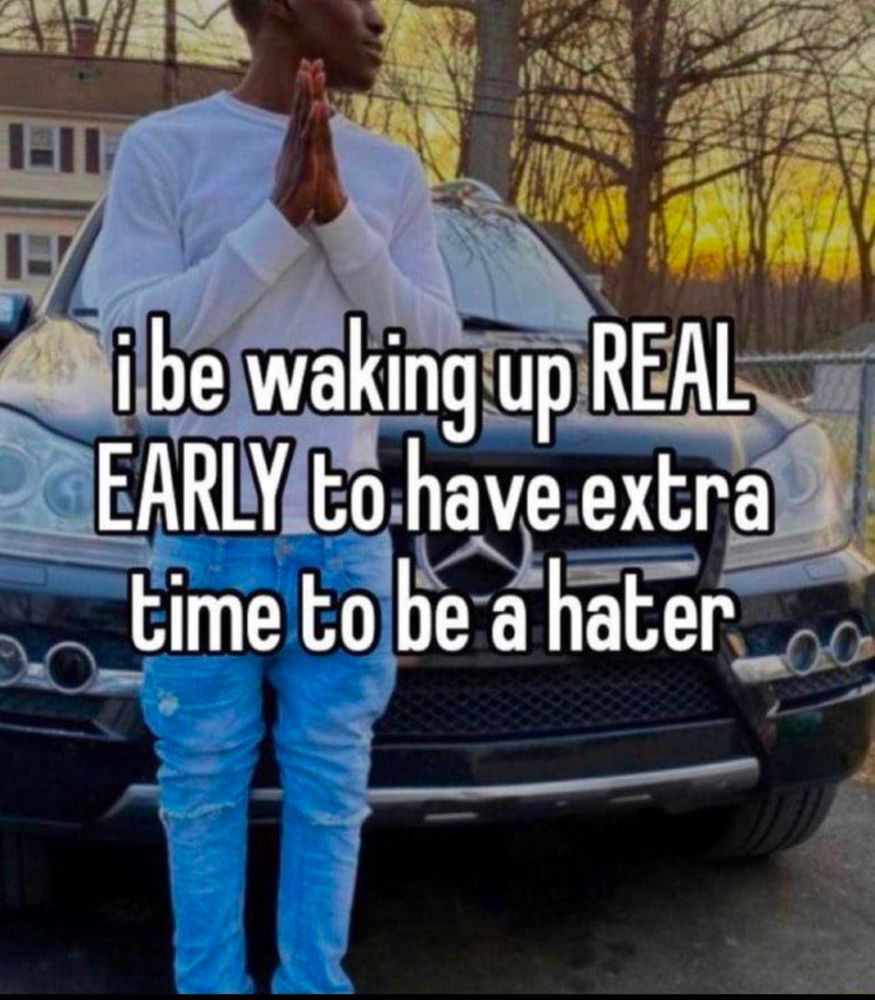 Young, black man and jeans and a white T-shirt with hands pressed together, staring off to the right. Text says: I be waking up REAL EARLY to have extra time to be a hater 