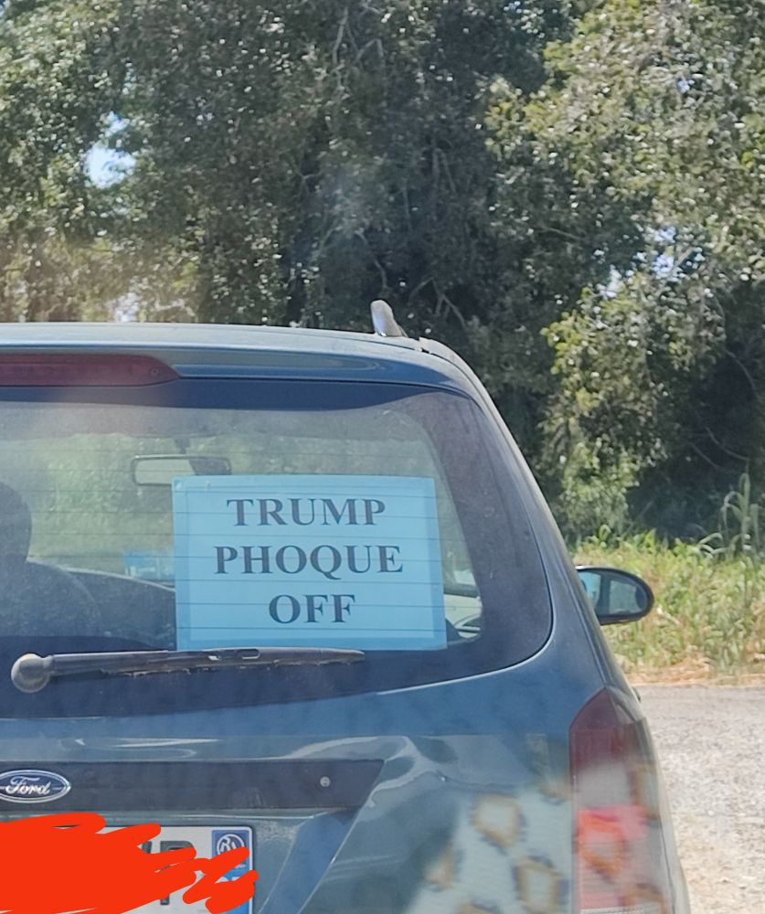 Voiture avec panneau "Trump phoque off"
