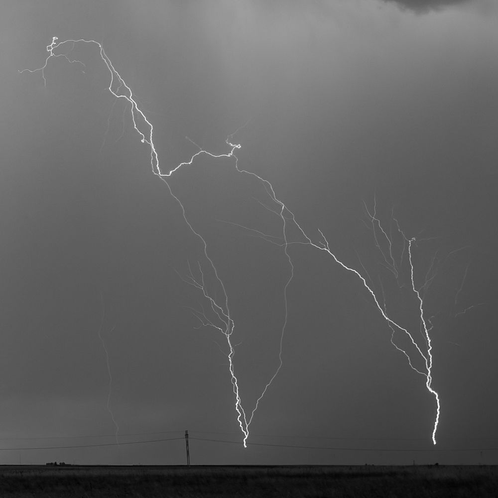 Triple upward lightning coming off the tops of wind turbines. Rendered in Black and White.