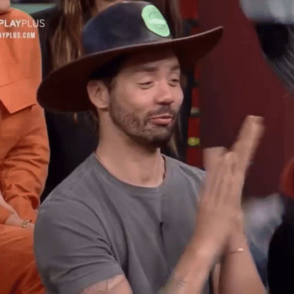 a man in a cowboy hat is clapping his hands .