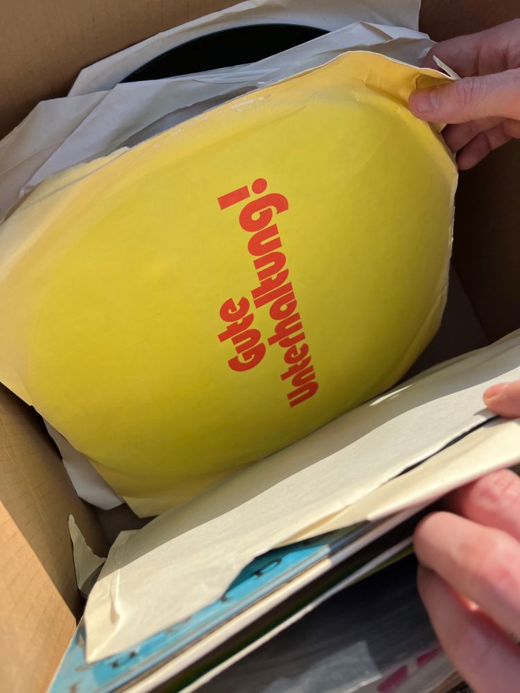 Eine gelbe Schallplatte mit dem roten Schriftzug „Gute Unterhaltung!“ in einer „zu verschenken“-Kiste an einem Sonntagmittag in Berlin.