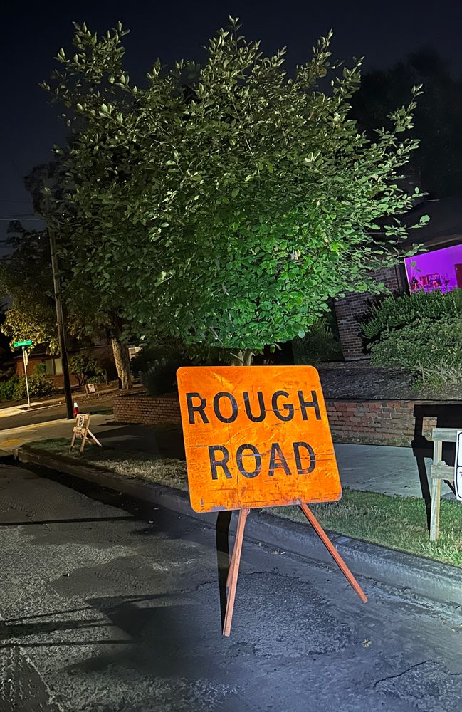 A cautionary road sign reading “ROUGH ROAD”
