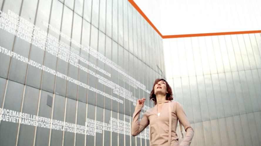 Générique Arte Info avec une femme au milieu d’un batiment a l’architecture tres angulaire