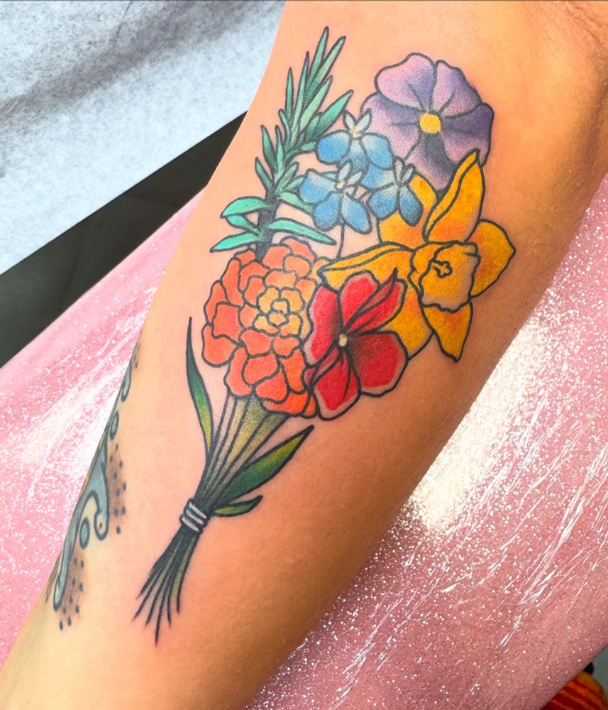 Forearm tatto of a flower bouquet. Each flower is a color of the rainbow, representing LGBTQIA Pride.