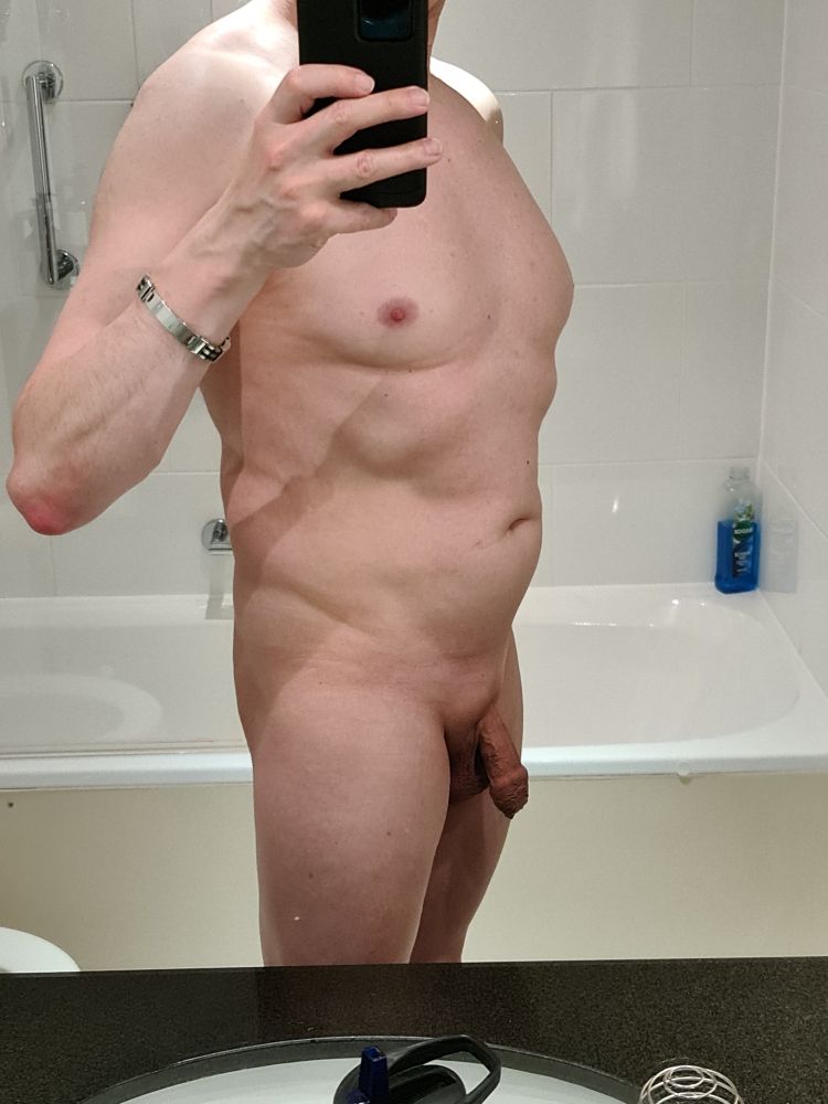 A nude photo of Bezel, standing in a bathroom