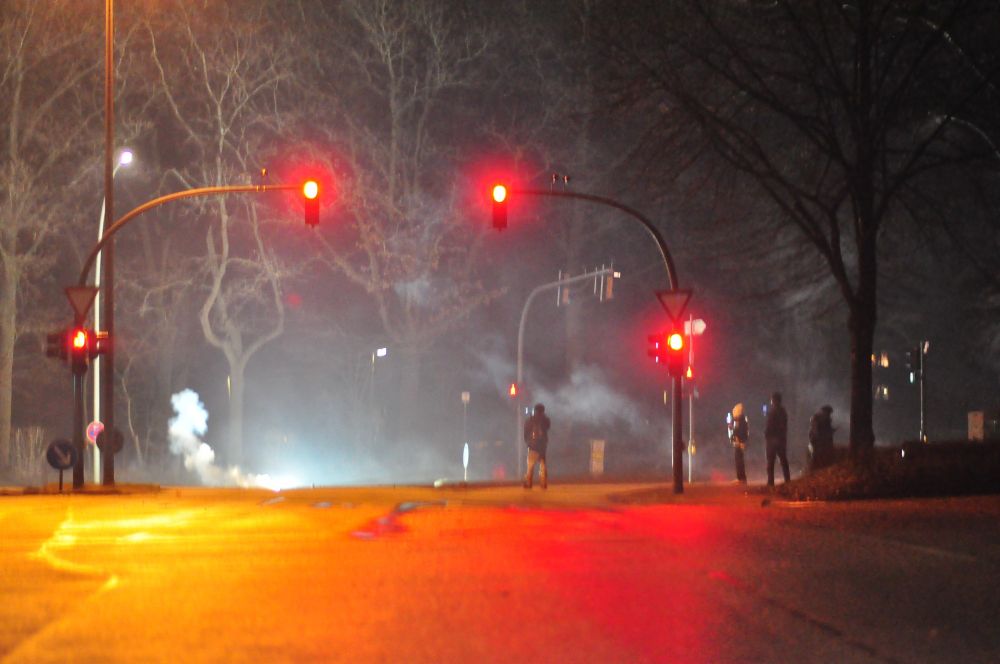 Mitternacht am 01.01.24 Kinder & Jugendliche den Rauch von den Böllern am fotografieren.  Mitten auf der Straße.Hintergrund Bäume , Rote Ampel & überall Rauch vom 🎆